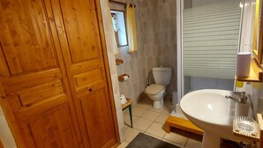 Een badkamer met een houten deur, een toilet, een wastafel en een spiegel.