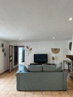 Uma sala de estar com um sofá, uma televisão e arte decorativa nas paredes.