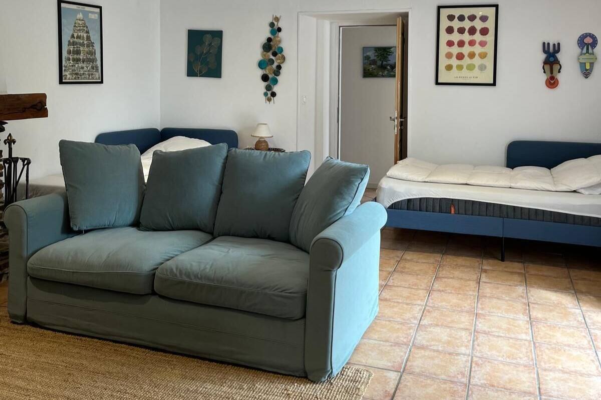 Un salon comprenant un canapé, un lit et un mur orné de diverses œuvres d’art.