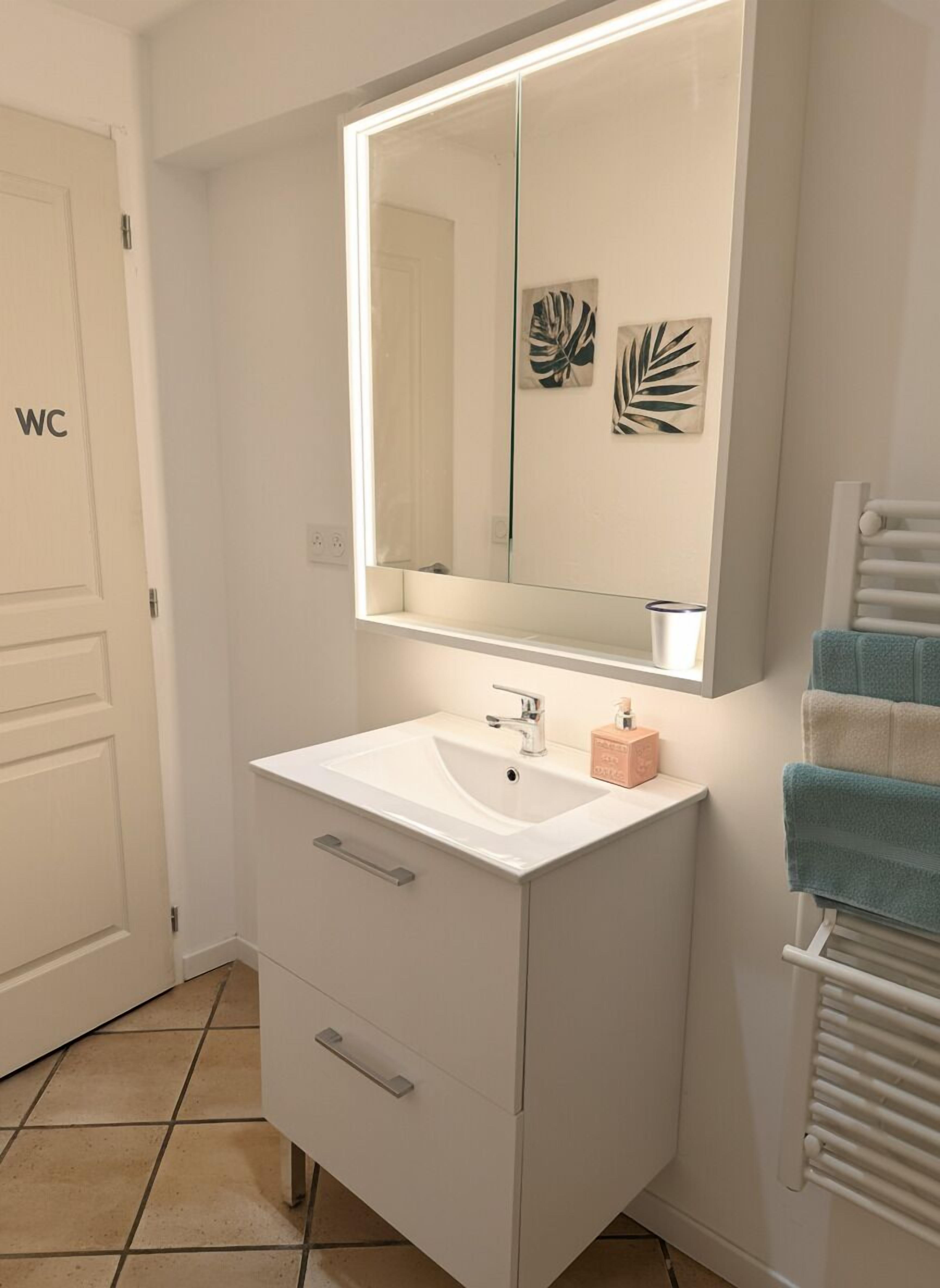 A bathroom with a white sink, a mirror, a towel rack, and a toilet.