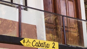 Ein Gebäude mit einem gelben Schild, auf dem "Cabana 2" steht, und einem Holzstapel unter dem Eingang.