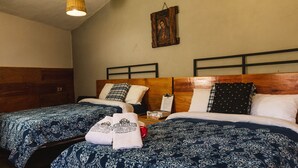 Ein Hotelzimmer mit zwei Betten, jedes mit einer gemusterten Tagesdecke, einem Holz-Kopfteil und einem an der Wand hängenden Gemälde.