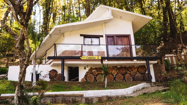 Ein zweistöckiges Haus mit einem Balkon, einer Holztreppe und einem Schild mit der Aufschrift 'Cabana 2'.