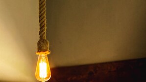 Ein Detailaufnahme einer an der Decke hängenden Kordel mit daran befestigter Glühbirne.