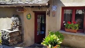 A building with a stone staircase, a door with a sign, a window with red flowers, and a sign indicating 'Sites de France'. - Les Copains à Bord - Gîte D'étape (Cans et Cévennes)