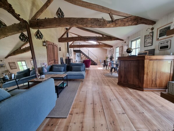 A spacious living area with a wooden floor, a blue sofa set, and a wooden cabinet. - Lariviere (Asques)