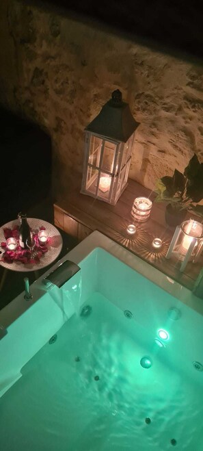 A hot tub with a green light, surrounded by candles and a lantern. - Lariviere (Asques)