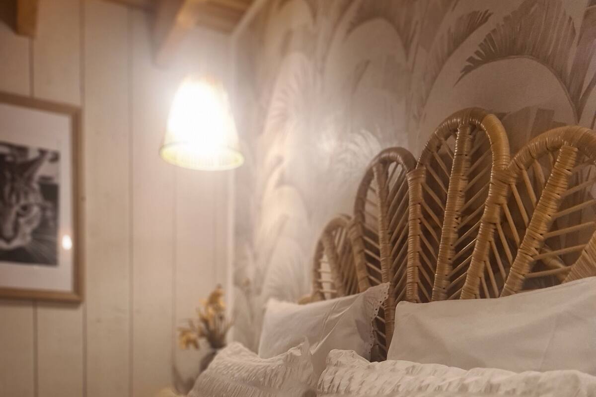 A bed with a textured white cover, several pillows, and a woven headboard.