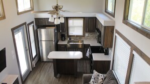A compact kitchen with a refrigerator, stove, and sink, a ceiling fan, and a window with blinds. - Outcast Landing - A Fisherman's Paradise (Cedar Creek)