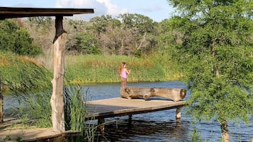 Une jetée en bois s’étendant sur une étendue d’eau calme, entourée d’une végétation luxuriante et d’arbres.