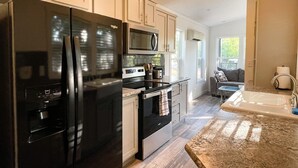 A modern kitchen with a large black refrigerator, a microwave, and a stove. There is a window providing natural light and a view of the outdoors. - Outcast Landing - A Fisherman's Paradise (Cedar Creek)