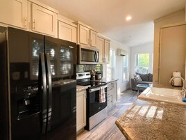 Una cocina moderna con un refrigerador negro grande, un microondas y una estufa. Hay una ventana que proporciona luz natural y vistas al exterior.
