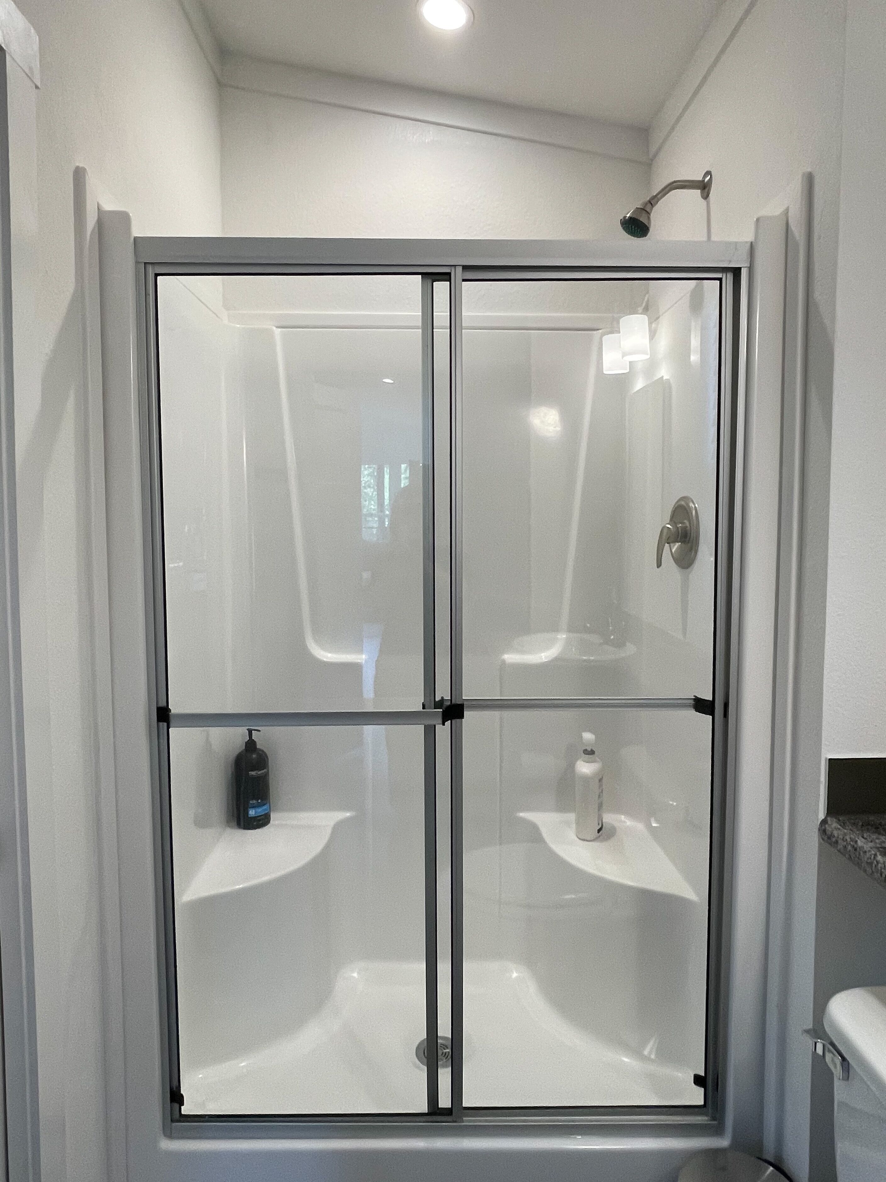 Une douche à l’italienne avec une porte en verre, un pommeau de douche amovible et deux lavabos.