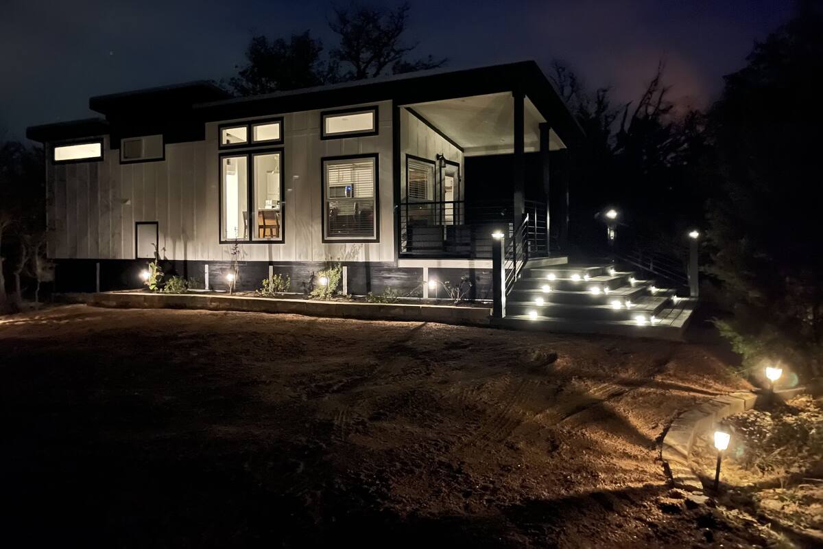 A modern house with large windows, a covered porch, and a staircase leading to the entrance.