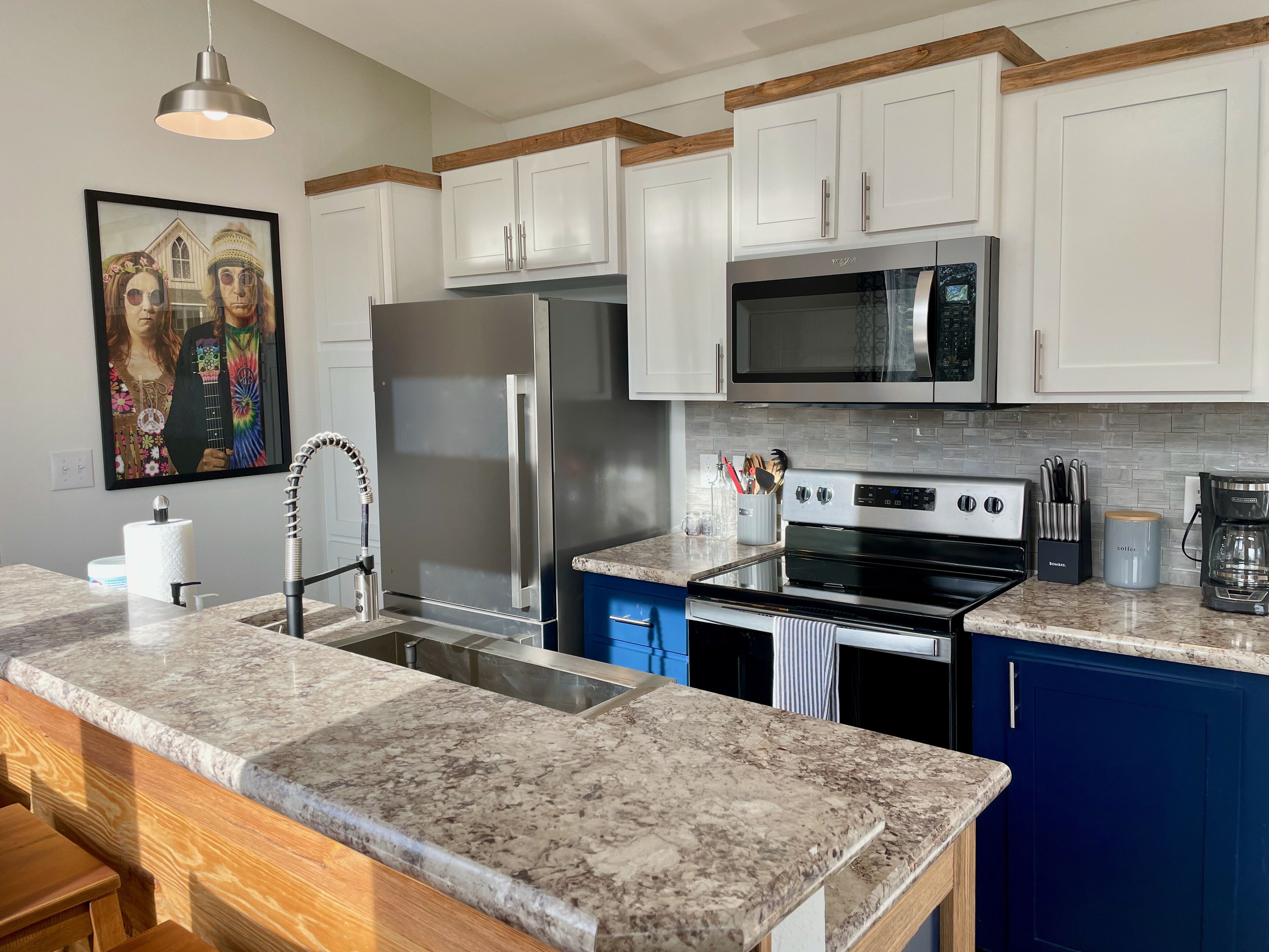 A kitchen with white cabinets, a stainless steel refrigerator, a microwave, an oven, and a granite countertop.