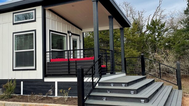 A modern house with a covered porch, a staircase, and a view of the surrounding landscape. - Outcast Landing - A Fisherman's Paradise (Cedar Creek)