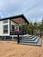 Una casa moderna con un porche cubierto, una escalera y vistas del paisaje circundante.