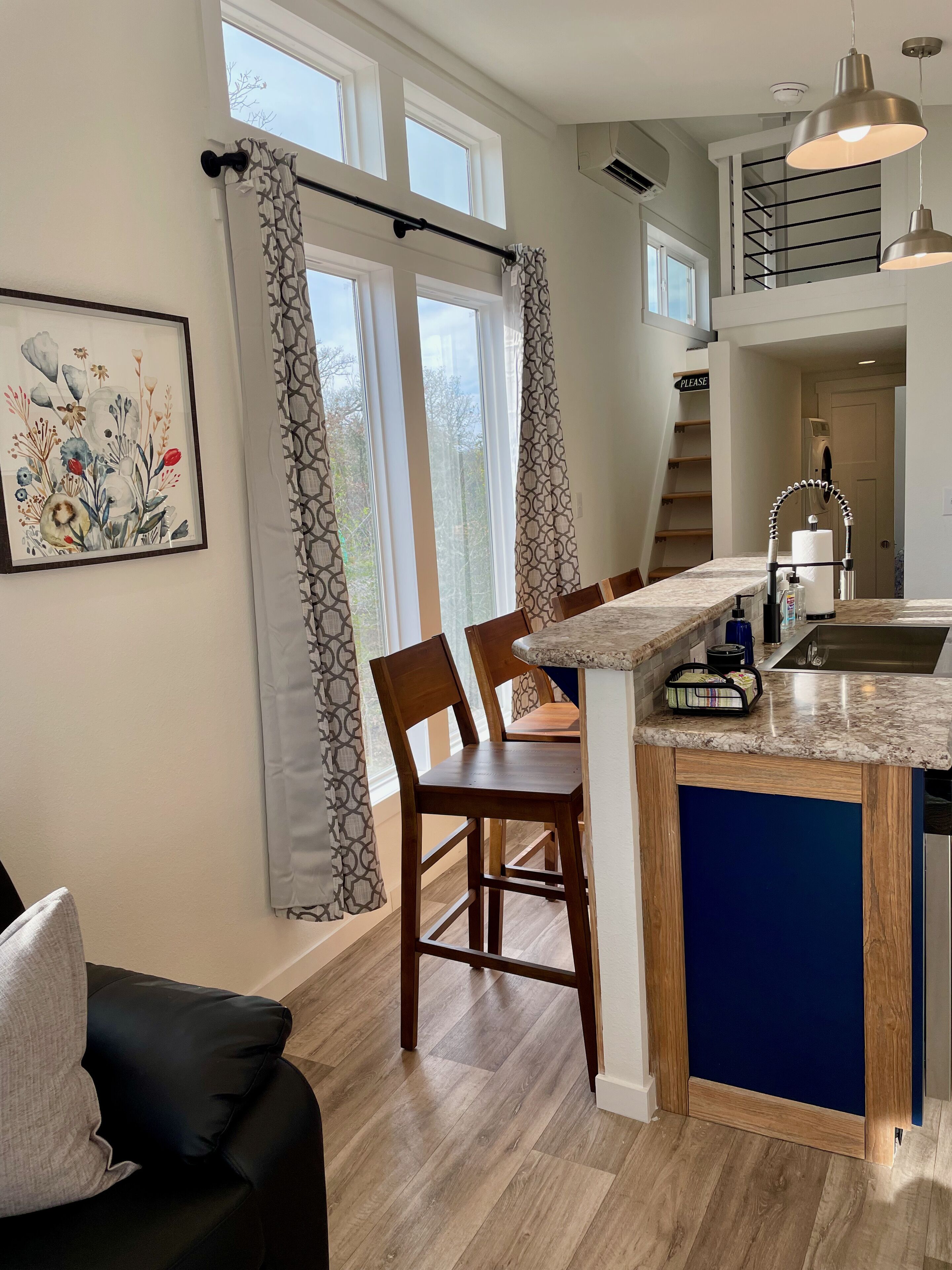 A modern kitchen with a central island, wooden chairs, and a dining table.