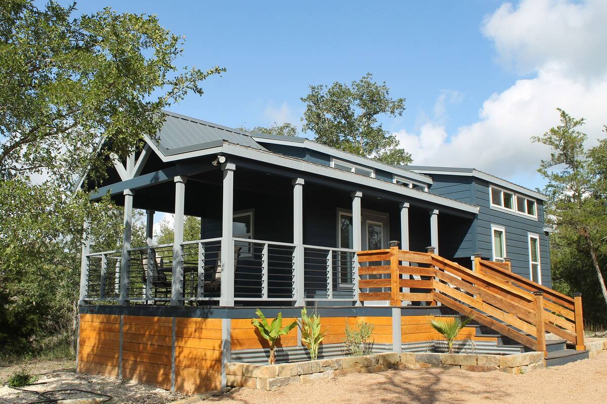 A two-story house with a covered porch and a wooden staircase leading to the entrance.