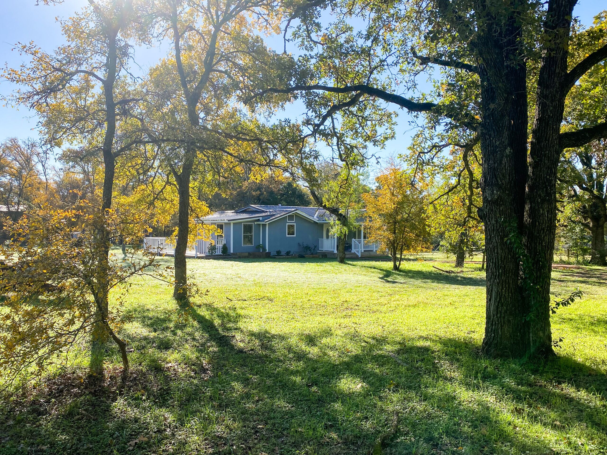 A house with a front porch, surrounded by trees with autumn foliage.