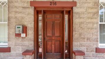 A wooden door with a number plate '216' above it, set in a stone building facade.