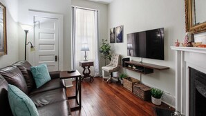 Una sala de estar con sofá de cuero, televisor, chimenea y puerta.