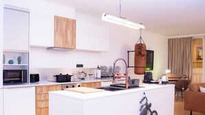A modern kitchen with white cabinetry, a central island, and a hanging light fixture. - R213 - Industrial Style Sanctum (Saint-Josse-ten-Noode)