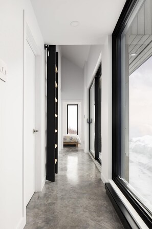 Enter a serene space with a hallway leading to a cozy bedroom featuring a bed with a patterned bedspread.