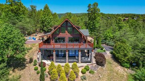 A log cabin with a balcony, surrounded by trees and a mountainous backdrop. - STUnning Views|Hot tub|FirePit|Easy Drive|Pool Table|Semi Secluded|Easy CheckOut (Sevierville)
