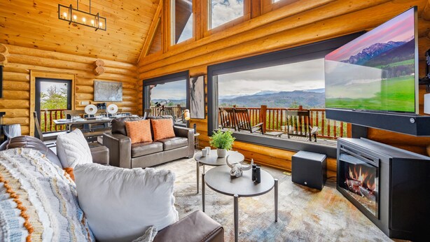 A cozy log cabin interior with a large TV, comfortable seating, and a scenic view. - STUnning Views|Hot tub|FirePit|Easy Drive|Pool Table|Semi Secluded|Easy CheckOut (Sevierville)