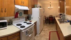 Una cucina compatta con piano cottura, forno a microonde, frigorifero e un angolo ristoro con tavolo e sedie.