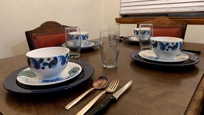 Una tavola da pranzo apparecchiata con stoviglie bianche e azzurre, tra cui ciotole, piatti e posate.