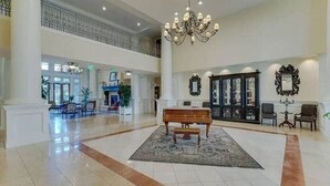 Um hall amplo com um candelabro, um piano e um tapete grande.
