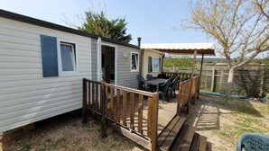 Une maison mobile dotée d’une terrasse, d’un espace salon extérieur et d’un patio couvert.
