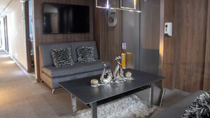 A modern living room with a sofa, a coffee table with decorative items, a mounted TV, and a number five sign on the wall. - Hotel Velero (Rionegro)