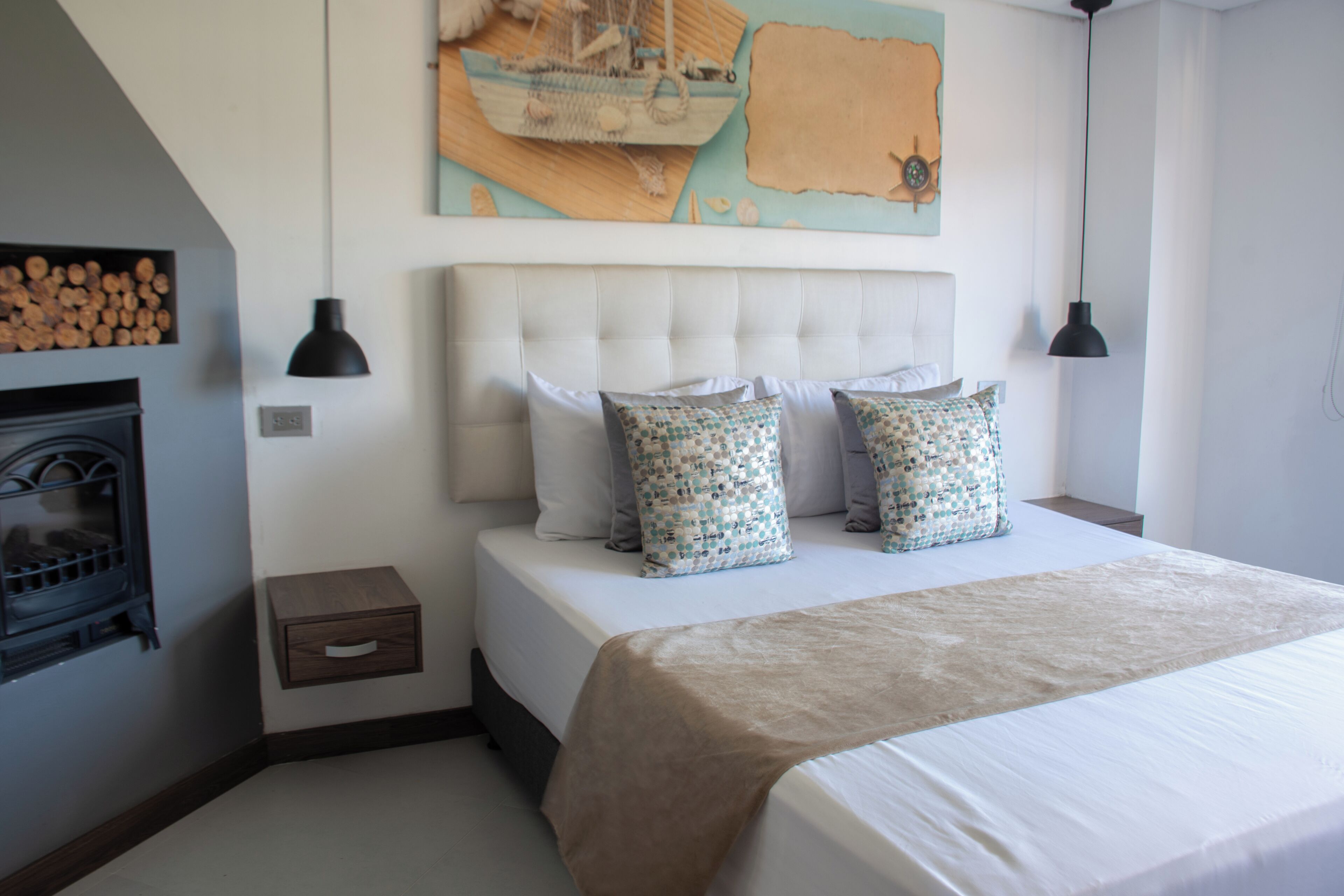 A bedroom with a large bed, a headboard, two bedside tables, a wall-mounted lamp, and a decorative wall piece.