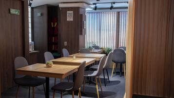 Une salle de conférence avec une table en bois, des chaises et une vue sur l’extérieur grâce à de grandes fenêtres.