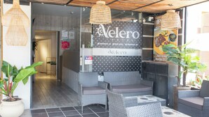 A hotel entrance with wicker furniture, a signboard, and a potted plant. - Hotel Velero (Rionegro)