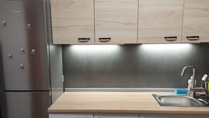 Eine Küche mit einem Edelstahl-Kühlschrank, Holzschränken, einer Holzarbeitsplatte und einem Spülbecken mit Armatur.