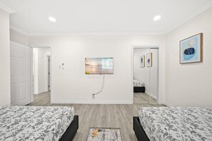 Un dormitorio moderno con dos camas, un espejo grande y obras de arte en las paredes.