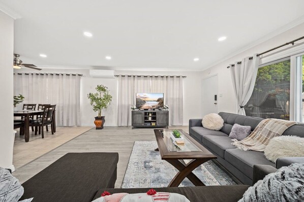 A modern living room with a grey sofa, a coffee table, and a TV in the background.