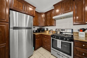 A kitchen with wooden cabinets, a stainless steel refrigerator, a gas stove, and an oven.