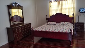A bedroom with a wooden bed, a dresser, a mirror, and a television on the wall. - Exquisite Accommodation in Gated Community (Versailles)
