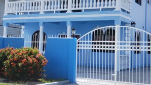 A two-story building with a blue facade, white balcony railings, and a white gate. - Exquisite Accommodation in Gated Community (Versailles)