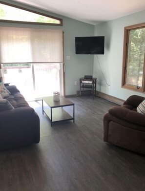 A living room with a sofa set, a coffee table, and a flat-screen TV mounted on the wall. - The Cabin @Lake George (Lake George)