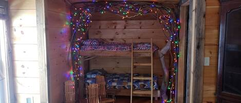 A cozy cabin interior with a wooden bunk bed, a rocking chair, and a small desk.