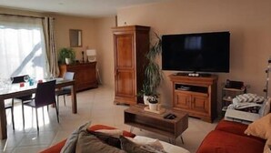 A living room with a TV, wooden cabinets, a dining table with chairs, and a sofa. - To complete (Aramon)