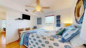 A bedroom with a bed, a ceiling fan, a TV, a desk, and a window with blinds. - A Pineapple Paradise (Bolivar Peninsula)
