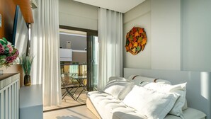Un soggiorno moderno con un divano bianco, una porta in vetro che dà su una zona esterna e un elemento decorativo a parete.