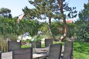 Enjoy al fresco dining in a serene garden setting with a table and chairs surrounded by lush greenery.